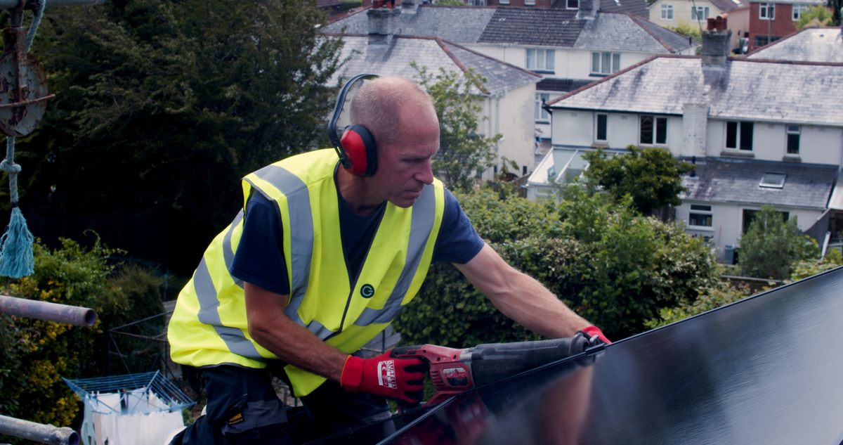 Solar panel installer placing solar panel on roof